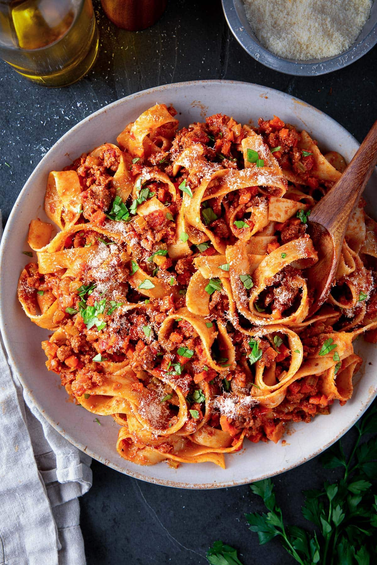 large plate of bolognese pasta with grated pecorino and minced basil.