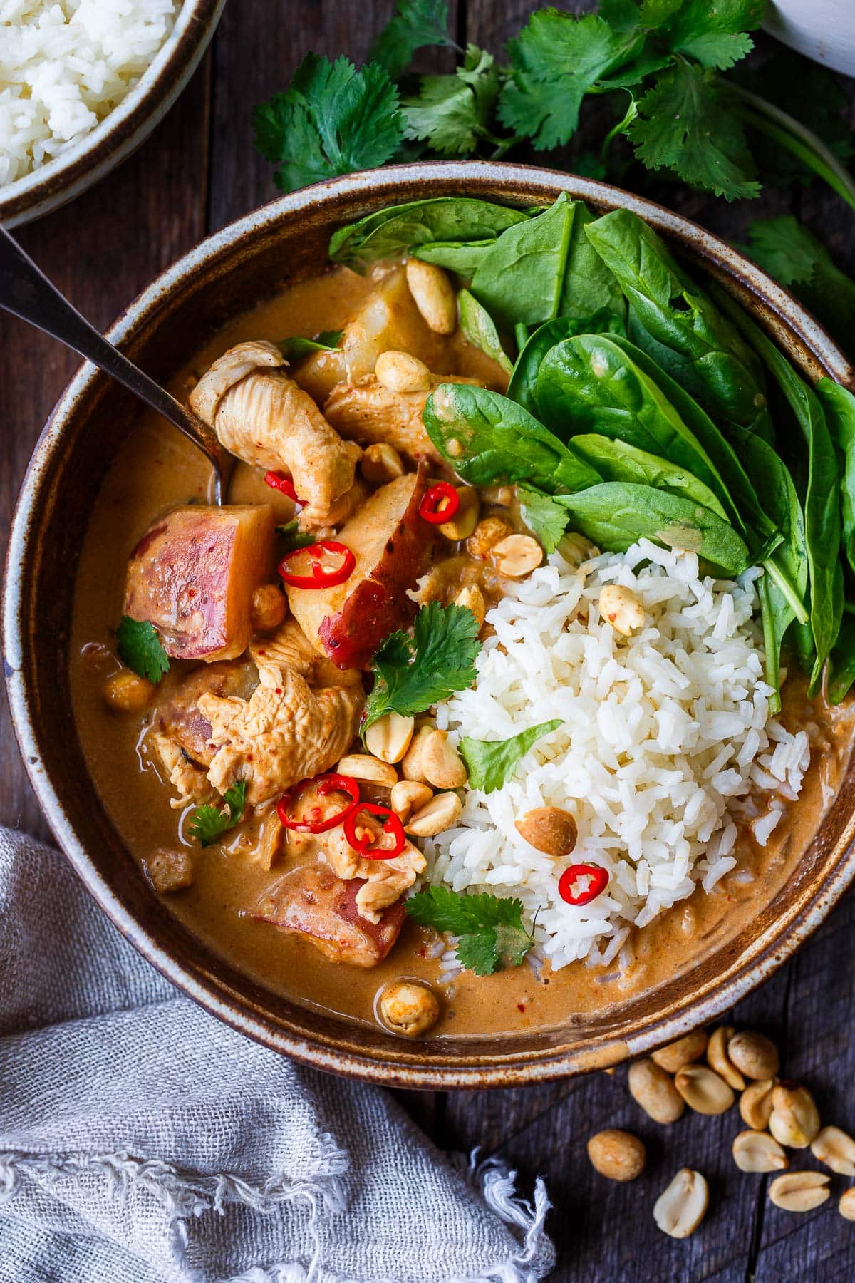 bowl of thai massaman curry with jasmine rice and spinach. 