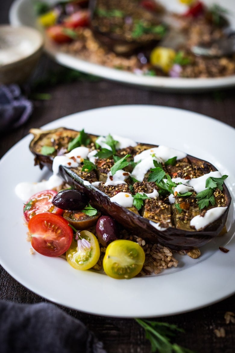 Crosshatched Zataar Roasted Eggplant served over rice with tahini sauce and parsley with cherry tomatoes and kalamata olives on the side. 