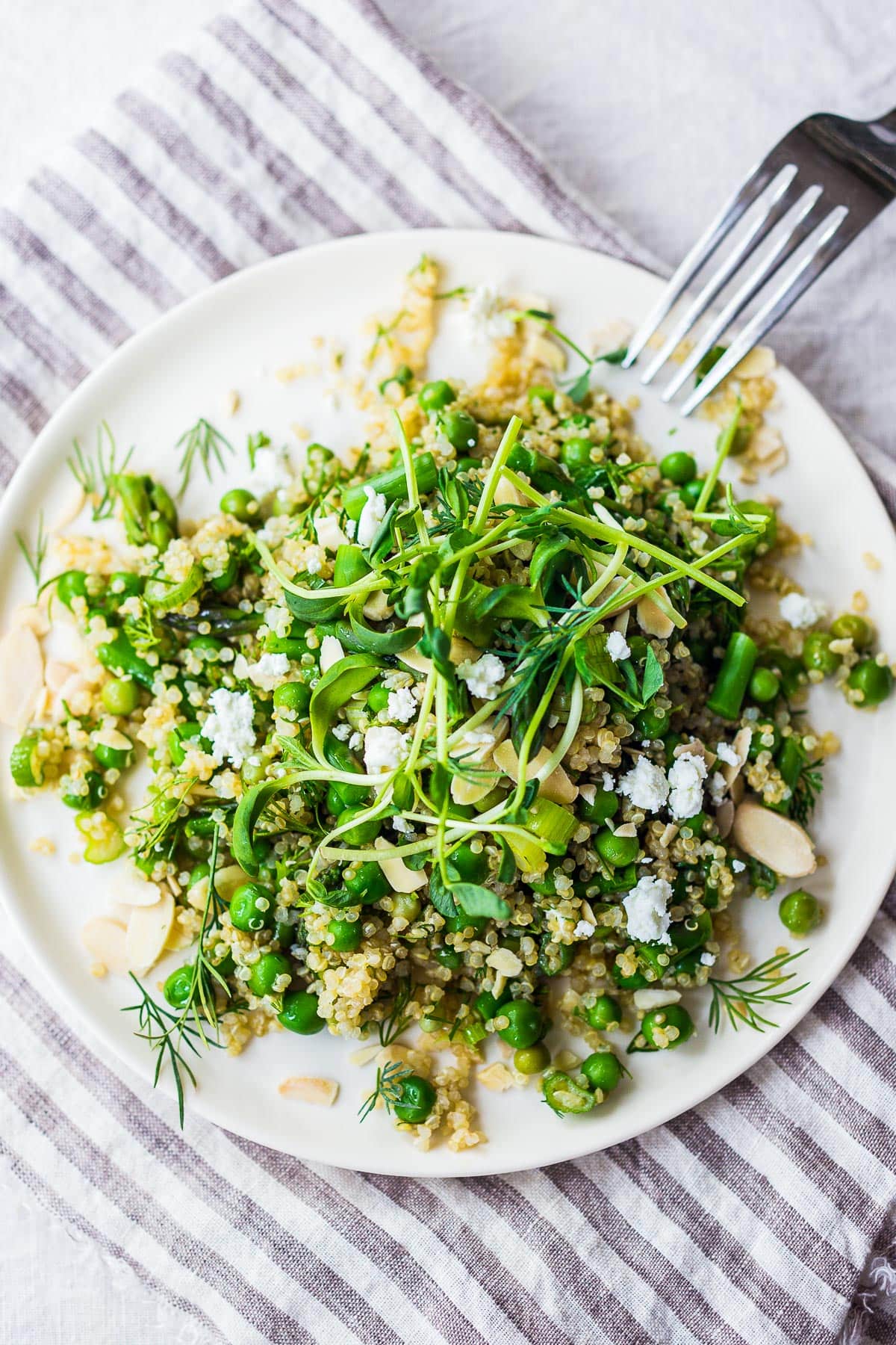 A simple recipe for Quinoa Asparagus Salad (aka Spring Tabouli) tossed with English peas, fresh dill, parsley, toasted almonds in a lemony dressing topped with optional avocado, goat or feta cheese. A healthy, flavorful salad that can be made ahead- perfect for special gatherings or midweek lunches! GF & Vegan adaptable!