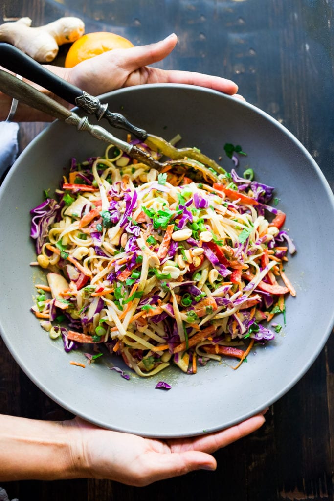 Thai noodle salad with crunchy veggies like purple cabbage, peppers, and carrots, topped with green onion and peanuts, in creamy peanut sauce. 